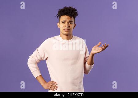 So what, why asking. Portrait of unbothered and careless, ignorant young man dont care on people rules, raising hand in dismay a Stock Photo