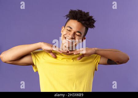 Close-up portrait of carefree handsome young man, do stretching exercises at home while on quarantine, hold hands sideways close Stock Photo