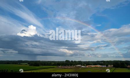 Aerial view shot with drone of a rainbow over stormy sky. Rural landscape with rainbow over dark stormy sky in a countryside at Stock Photo