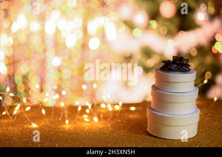 Three round gift boxes on a golden bokeh background with lights. new year and Christmas background. mock up Stock Photo