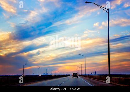 The sun sets over the City of Mobile as Interstate 10 traffic heads west on the Mobile Bayway, Oct. 23, 2021, in Mobile, Alabama. Stock Photo