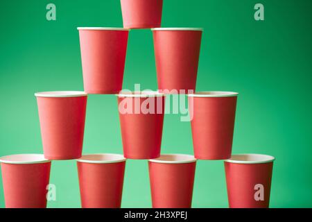 Pyramid of pink paper cups on green background. Stock Photo