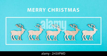 Wooden reindeers in a row on a blue colored background, merry christmas greeting card, wintertime Stock Photo