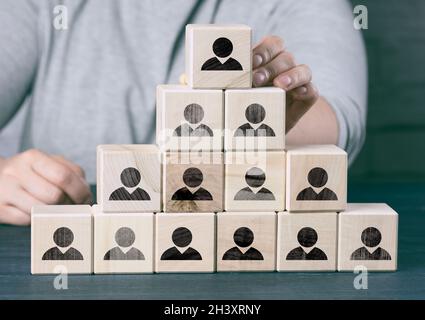 Female hand holds a wooden block on a blue background. Recruitment concept, teamwork, effective management. Stock Photo