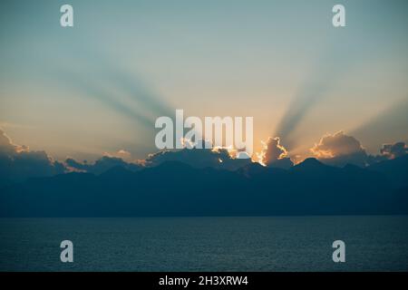 Dramatic sunset rays through cloudy dark sky over the ocean Stock Photo