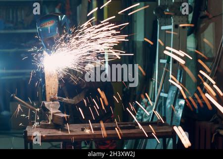 Man in mask cuts metal with plasma cutter. Helmet and spakrs Stock Photo
