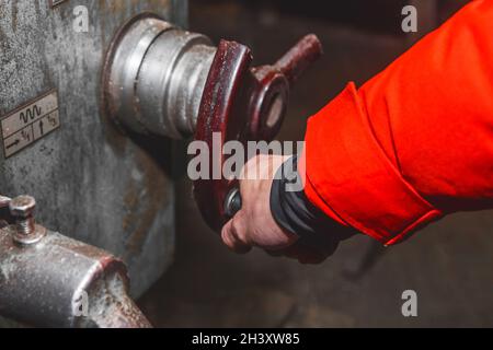 The hand of a man worker in a suit controls the milling machine by the handle in an industrial plant. Stock Photo
