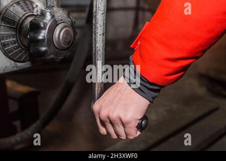 The hand of a working man holds the handle and controls the work of the milling machine. Stock Photo