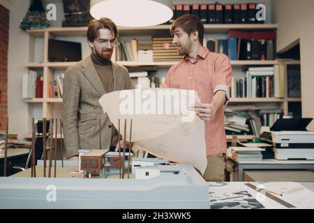 Architect with blueprints and layout design project at architectural bureau Stock Photo
