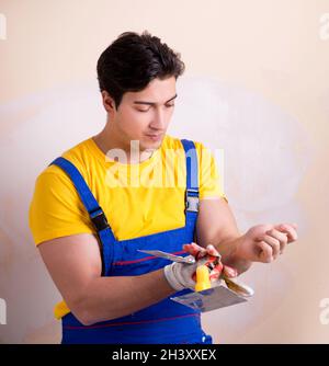 Young contractor employee applying plaster on wall Stock Photo