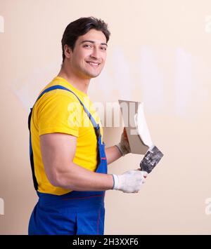 Young contractor employee applying plaster on wall Stock Photo