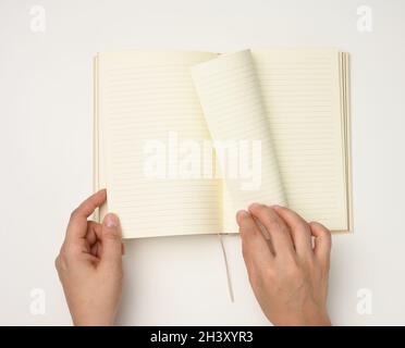 Two female hands hold an open notebook with blank white sheets on a white background Stock Photo