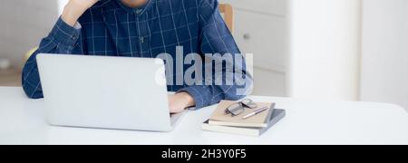 Hand of young man working on laptop computer on table at home office, male typing keyboard notebook on desk, businessman surfing to internet online or Stock Photo