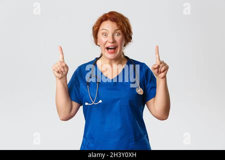 Medicine, healthcare and coronavirus concept. Excited and happy, middle-aged redhead nurse, doctor react to amazing big news, po Stock Photo