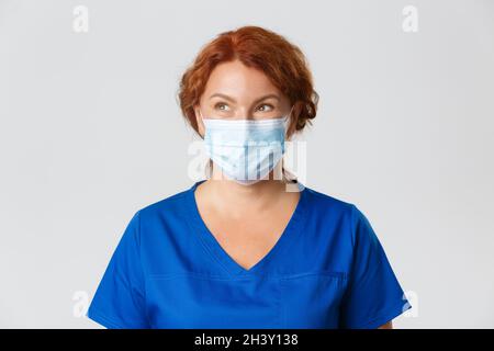 Medical workers, covid-19 pandemic, coronavirus concept. Thoughtful smiling female doctor, middle-aged nurse or physician in fac Stock Photo
