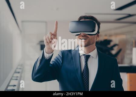 Smiling bearded businessman in 3d goggles using augmented reality in work Stock Photo