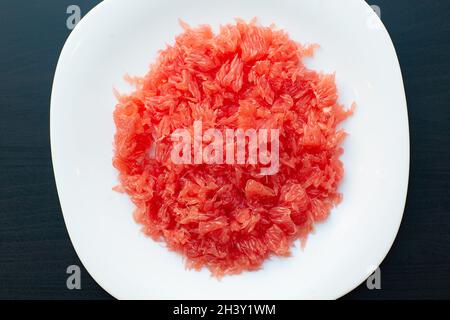 Red grapefruit fiber close-up. Fresh juicy cutted grapefruit without seeds and section shell on white plate Stock Photo