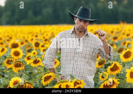 Man farmer standing in a sunflower field. Stock Photo