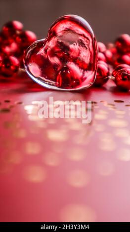 Shining transparent heart and red beads. Perfect Valentine's Day greeting card background. Vertical image in red tone Stock Photo