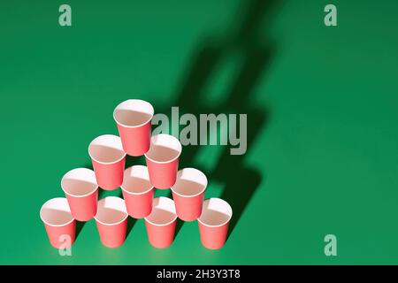 Pyramid of red paper cups on green background with copy space Stock Photo