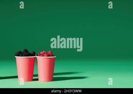 Fresh berries in red cup on green background. with copy space Stock Photo