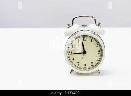 White round alarm clock stands on the table Stock Photo