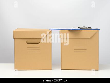 Two cardboard boxes made of brown corrugated cardboard are on a white table, moving, goods delivery Stock Photo