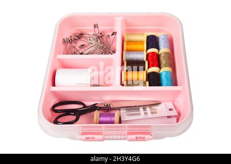 There are threads scissors and needles in a pink plastic sewing box. Isolated on white background Stock Photo