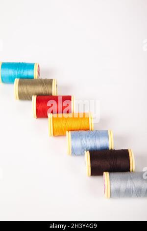 Spools and bobbins of thread for sewing in different colors, isolated on white background Stock Photo