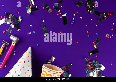 Party tinsel and colorful cups close up on purple background Stock Photo