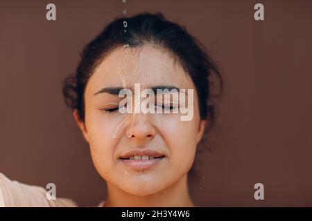 Stressed woman suffering of heatstroke refreshing with cold water outside. Weather abnormal heat concept. Stock Photo