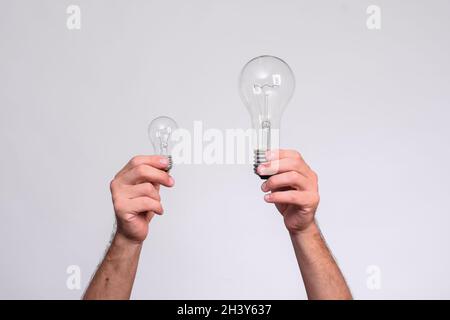 Two light bulbs in men's hands. large and small incandescent lamps. Stock Photo