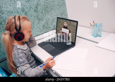 Young student little girl with tacher holds white poster with quadratic equation in hands on laptop screen learning and preparin Stock Photo