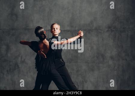 Two Tango dancers in black costume dancing in ballroom Stock Photo