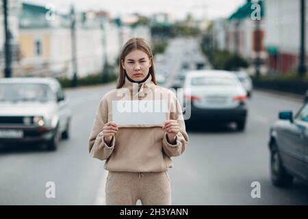 Young woman hold white paper poster in hand. Girl with white blank template sheet in hands. Stock Photo