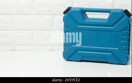 Closed blue plastic tool case stands on a white table Stock Photo