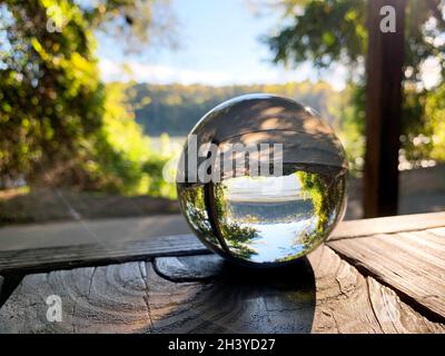 Inverted river seen through glass ball on wood table in early morning Stock Photo