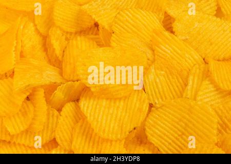 close-up full frame yellow wavy potato chips heap background Stock Photo