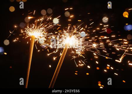 Bright glittering burning sparkler on dark background Stock Photo