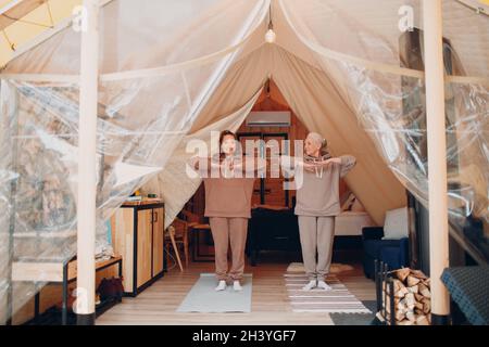 Woman senior and young relaxing at glamping camping tent. Women family  elderly mother and young daughter doing yoga and meditation indoor. Modern  zen-like vacation lifestyle concept Stock Photo - Alamy