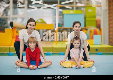 Kids girl and boy doing stretching exercises in gym at kindergarten or elementary school. Children sport and fitness concept. Stock Photo