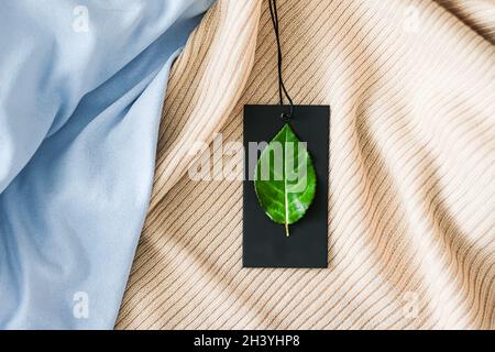 Green leaf on clothing tag and organic fabric background, sustainable  fashion and brand label concept Stock Photo - Alamy