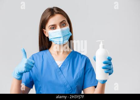 Covid-19, preventing virus, healthcare workers concept. Serious female nurse or doctor in blue scrubs, medical mask and gloves, Stock Photo