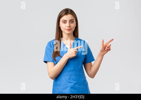 Healthcare workers, prevent virus, insurance and medicine concept. Young nurse or doctor in blue scrubs pointing fingers right, Stock Photo