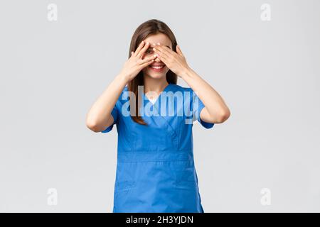 Healthcare workers, prevent virus, insurance and medicine concept. Cute female nurse or doctor in clinic wearing scrubs, cover e Stock Photo