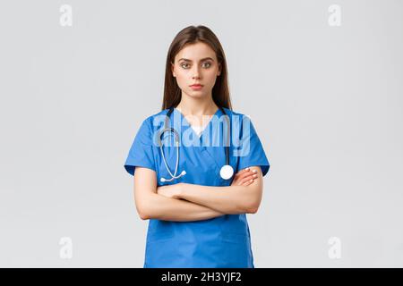 Medical workers, healthcare, covid-19 and vaccination concept. Serious and determined professional female nurse, doctor in blue Stock Photo