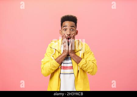 Delighted surprised nice african american guy in stylish outfit with beard and curly haircut folding opened mouth in wow sound g Stock Photo