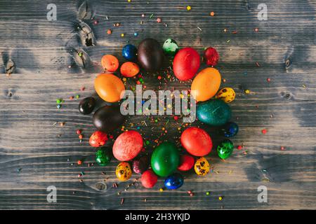 A ring of Easter eggs on a wooden background. A circle of colorful eggs and decorative sugar powder. Easter backgrounds Stock Photo