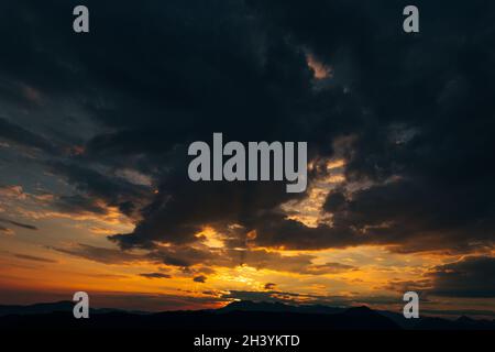 Gloomy black clouds and fiery orange sunset. Stock Photo