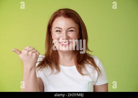 Come visit our store. Cheerful pleasant friendly charming redhead middle-aged woman entrepreneur inviting check-out promo smilin Stock Photo